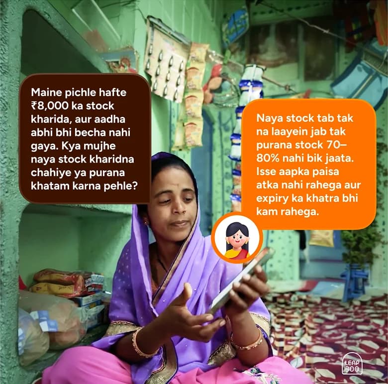 Shopkeeper using Vyapar Mitra on a phone in her store; chat bubbles show stock advice in Hindi